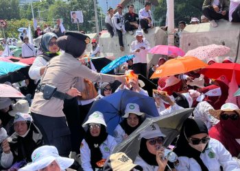 Polisi Bagikan Air Mineral dan Roti kepada Massa Aksi Damai Guru di Silang Selatan Monas