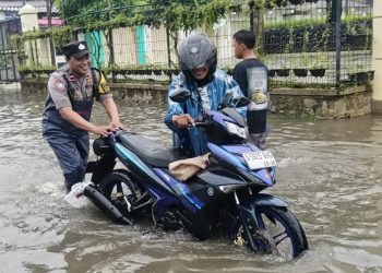 Bhabinkamtibmas Desa Satriajaya Pantau Banjir Akibat Luapan Kali Bekasi, Sigap Bantu Warga Dorong Kendaraan