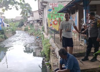 Antisipasi Banjir, Bhabinkamtibmas Gelora Bersama Babinsa Cek Ketinggian Air Kali Grogol Utara